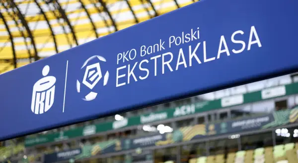 Niebieski baner z logo PKO Bank Polski Ekstraklasa na tle stadionu.